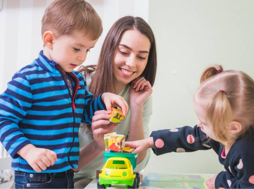 A care worker is playing with two baby