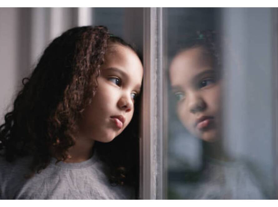 A little girl is looking out the window.