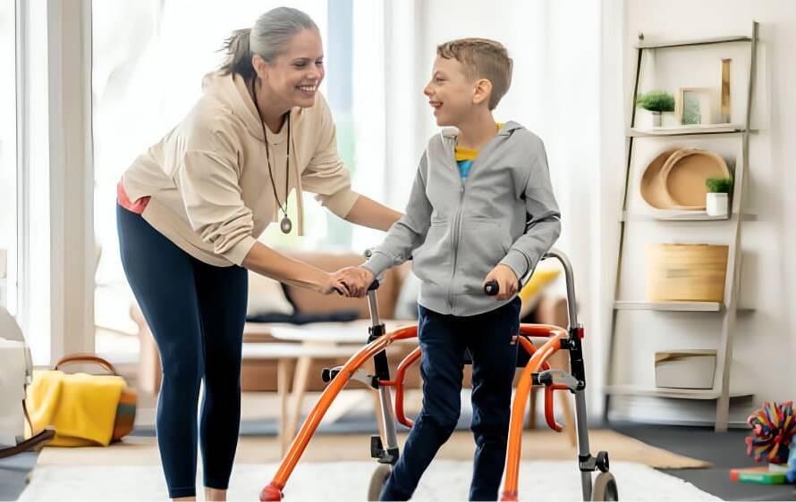 A care worker is helping a boy walk