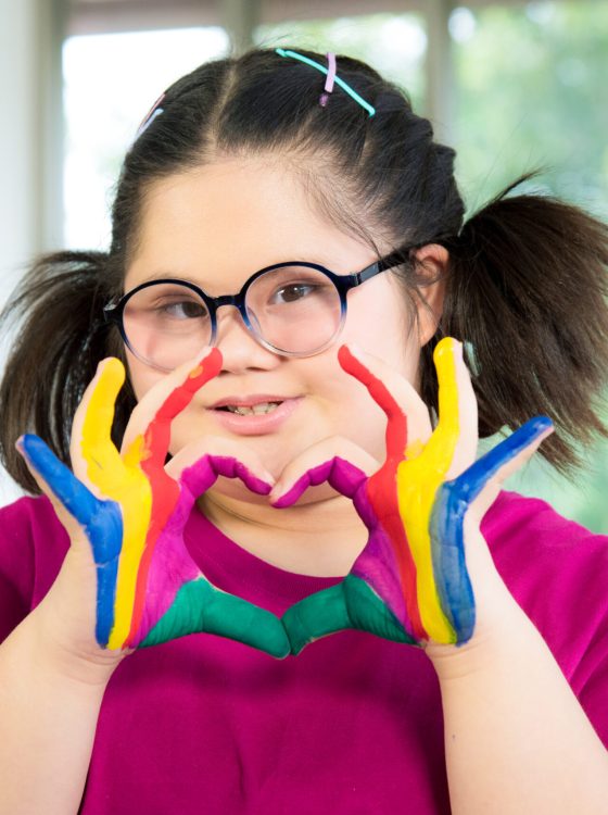 Portrait of Asian autism disabled child kid complex genetic disorders down syndrome girl with colorful painted hands